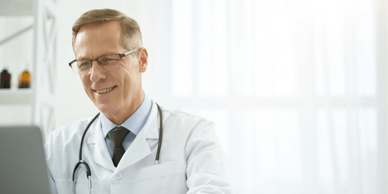 caucasian male doctor sitting at desk working on computer
