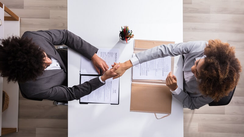 hiring manager shaking hands with candidate at job interview